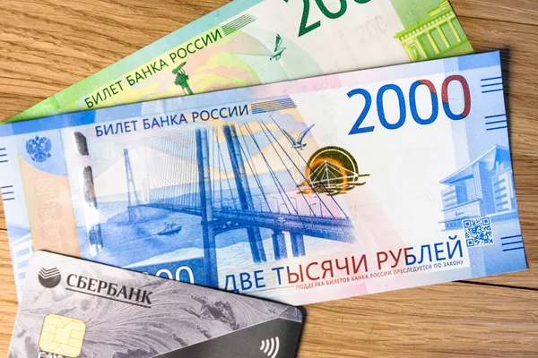 Pengar och Sberbank kreditkort på en vedartad bakgrund Stockbild