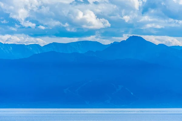 Lac Baïkal dans une brume bleuâtre avec des silhouettes de montagnes — Photo