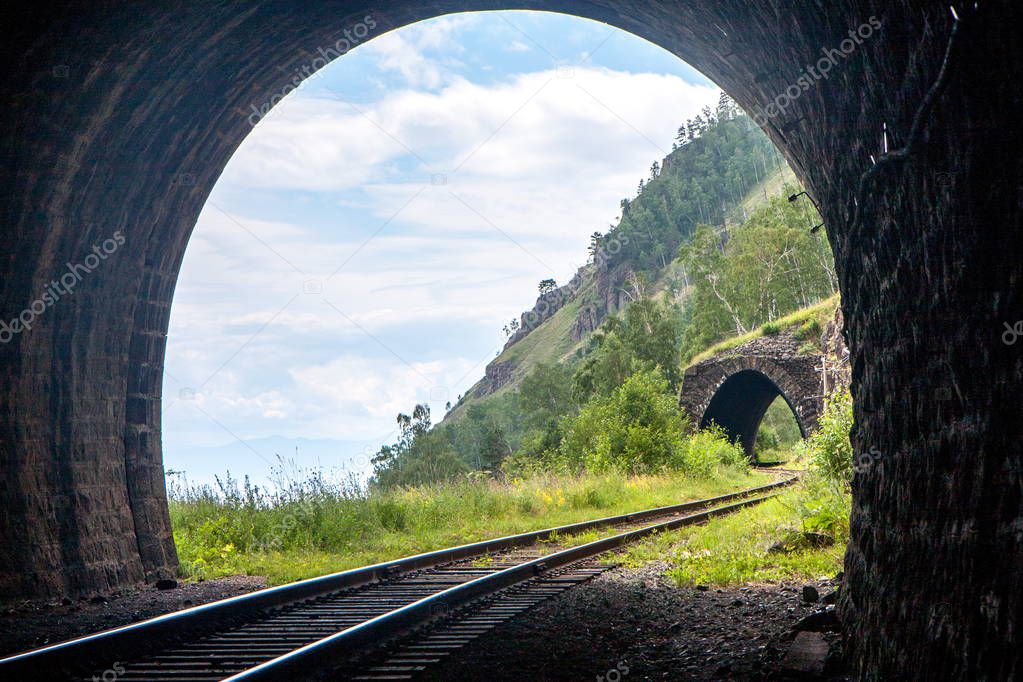 Light with a beautiful landscape at the end of a stone railway tunnel in the mountains