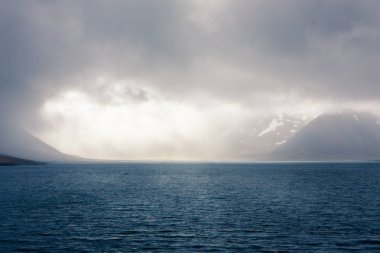 Dağlar güzel güneş ışığı ve pus ile, su sütunu üzerinde yükselir