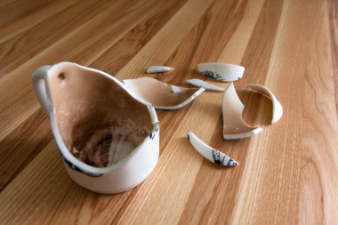 Kırık beyaz kupa, ahşap arka planda kırıkları var.