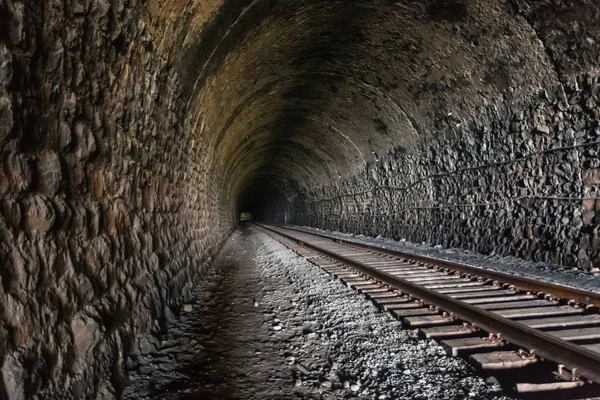 Mörk och lång järnvägstunnel med ledningar och skenor som sträcker sig in i avståndet Stockbild