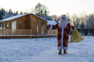 Xmas, soğuk, Aralık. Noel Baba hediye çanta ile kış aylarında karla kaplı sahada olacak.