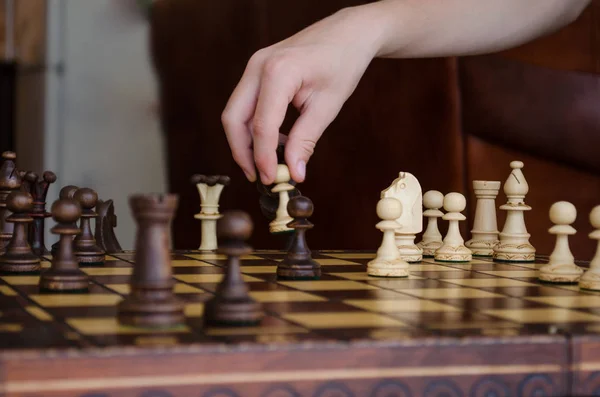 Wide cropped image of a human hand moving a chess piece of a light pawn