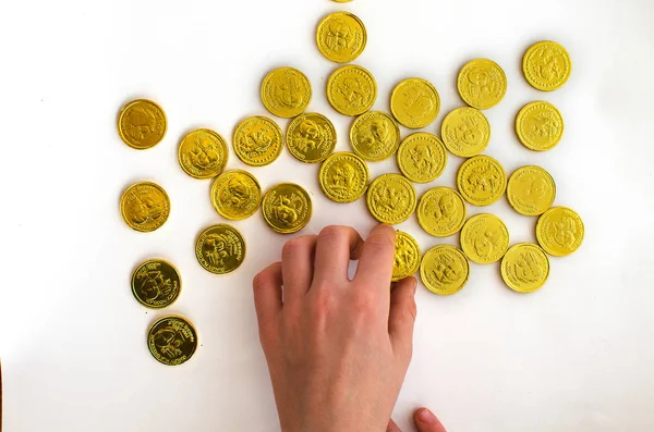 Bando de moedas de ouro de chocolate com a mão do homem no fundo branco — Fotografia de Stock