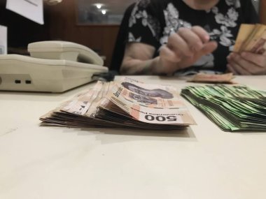 Bej renkli bir masaya yığılmış yaklaşık 500 Meksika banka notu banknotları