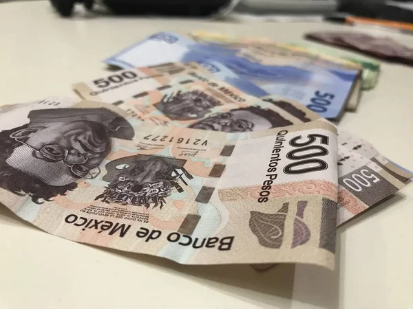 Many mixed Mexican peso bills spread over a beige desk — Stock Photo, Image