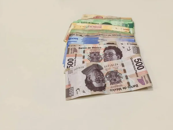 Muchos billetes mixtos de peso mexicano repartidos sobre un escritorio beige — Foto de Stock