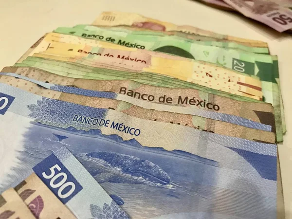 Muitas contas de peso mexicanas mistas espalhadas por uma mesa bege — Fotografia de Stock