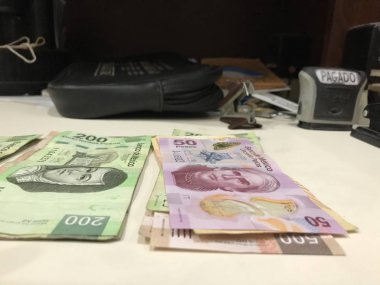 Birçok Meksika peso faturaları dağıtılan ve bej renkli bir masaya yayıldı