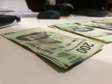 Beş yüz iki yüz Meksika pesosu birçok faturaları dağıtılan ve bej renkli bir masaya yayıldı
