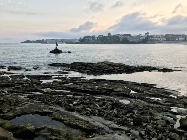 Yaz aylarında bulutlu bir gün boyunca Sanxenxo Silgar plaj sahilden deniz ve kayaların görünümü