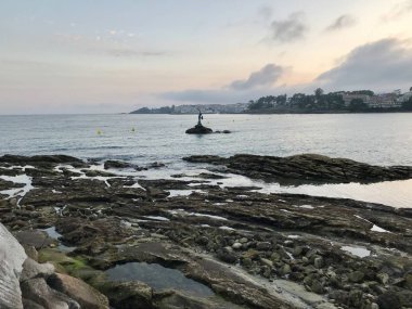 Yaz aylarında bulutlu bir gün boyunca Sanxenxo Silgar plaj sahilden deniz ve kayaların görünümü