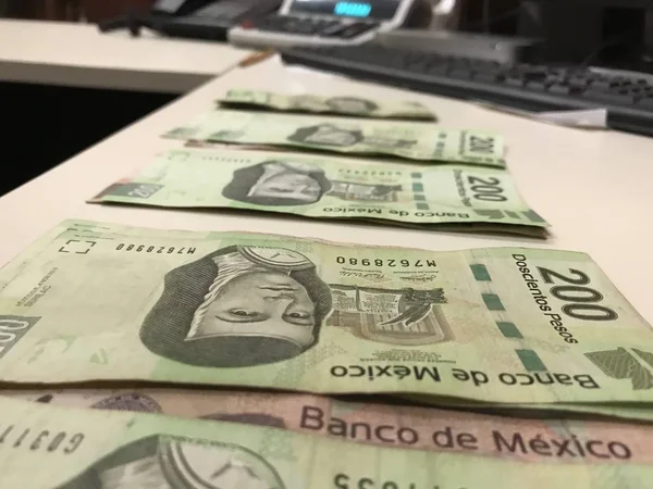 Many mexican pesos bills distributed and spread on a beige colored desk — Stock Photo, Image