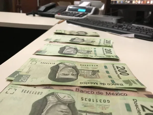 Many mexican pesos bills distributed and spread on a beige colored desk — Stock Photo, Image