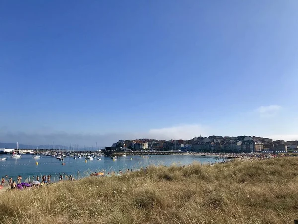 Vista de un campo con hierba seca y la playa durante un hermoso día de verano en Sanxenxo Galicia España —  Fotos de Stock