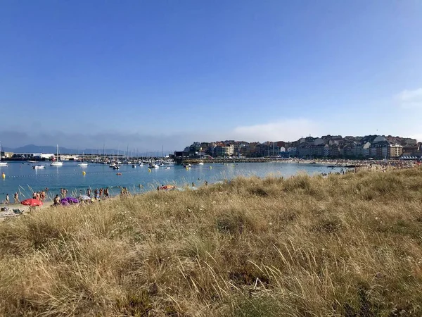 Uitzicht op een veld met droog gras en het strand tijdens een mooie zomerdag in Sanxenxo Galicië Spanje — Stockfoto