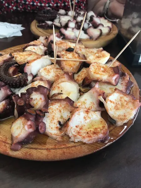 A wooden plate with a helping of "pulpo a feira" style boiled octopus — Stock Photo, Image