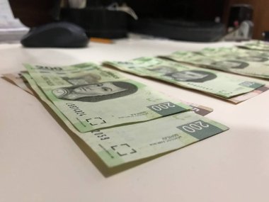 Beş yüz iki yüz Meksika pesosu birçok faturaları dağıtılan ve bej renkli bir masaya yayıldı