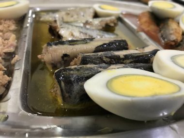 Mavi damalı masa örtüsü üzerine yerleştirilen paslanmaz çelik tepside yarıya, sardalye ve ton balığında kesilmiş pişmiş yumurta