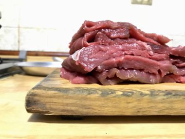 Mutfak tezgahında ahşap bir tahta üzerinde kesilmiş sığır filetosu