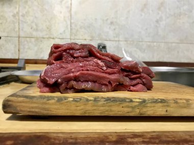 Mutfak tezgahında ahşap bir tahta üzerinde kesilmiş sığır filetosu