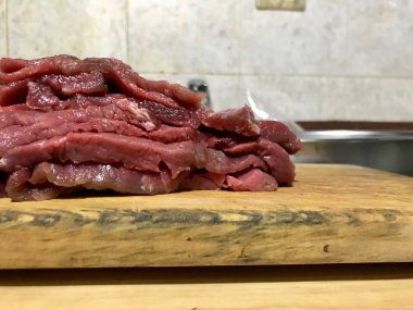 Mutfak tezgahında ahşap bir tahta üzerinde kesilmiş sığır filetosu