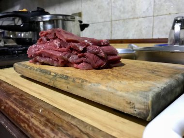 Mutfak tezgahında ahşap bir tahta üzerinde kesilmiş sığır filetosu