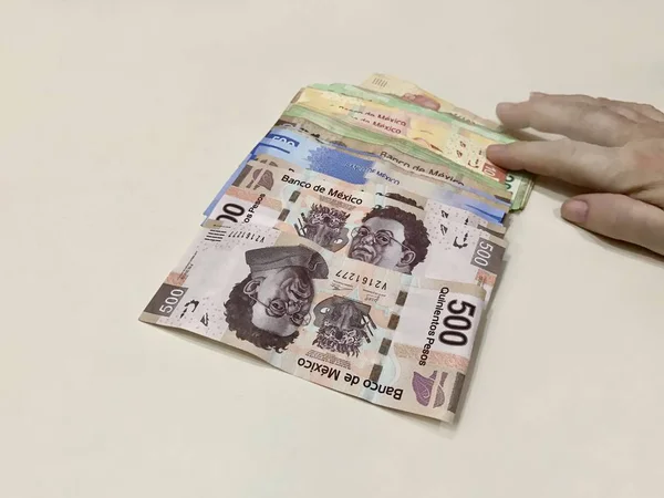 许多混合墨西哥比索钞票散布在一张米色的桌子上 — 图库照片