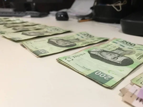 Many mexican pesos bills distributed and spread on a beige colored desk — Stock Photo, Image