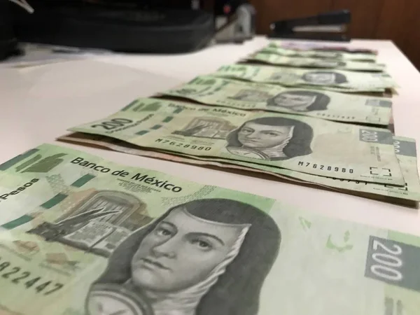 Many mexican pesos bills distributed and spread on a beige colored desk — Stock Photo, Image