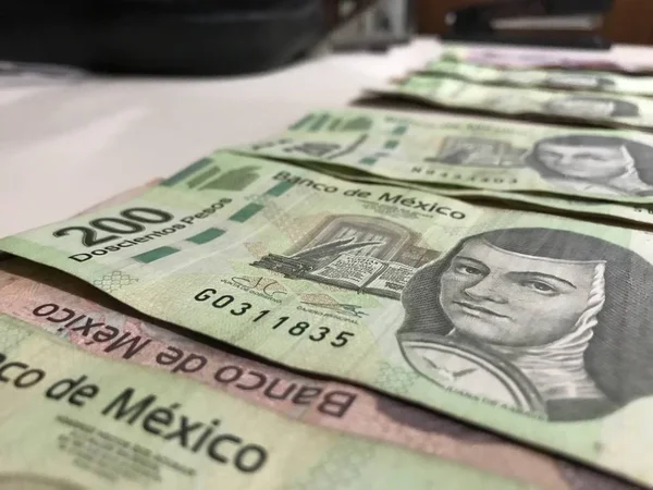 Many mexican pesos bills distributed and spread on a beige colored desk — Stock Photo, Image