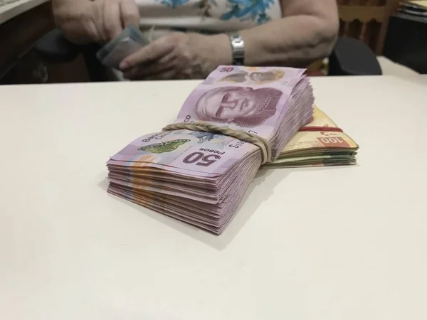 Algunos billetes de dinero en peso mexicano apilados en una mesa de color beige —  Fotos de Stock