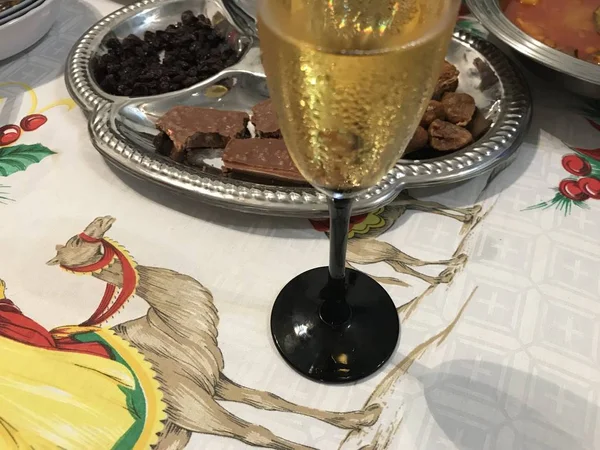 Jantar de Natal com taça de champanhe na frente e bandeja de aço inoxidável com chocolate, figos e passas no fundo . — Fotografia de Stock