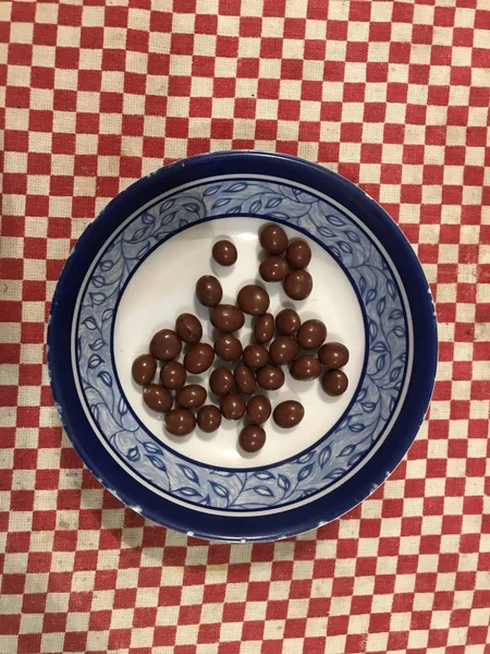 Copa de pasas cubiertas de chocolate sobre un fondo de mantel rojo —  Fotos de Stock