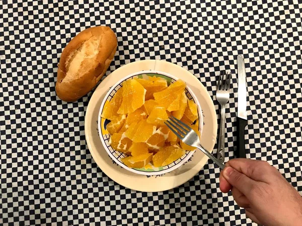 Draufsicht auf eine Schüssel mit gehackten Orangen mit einem Stück Brot links — Stockfoto