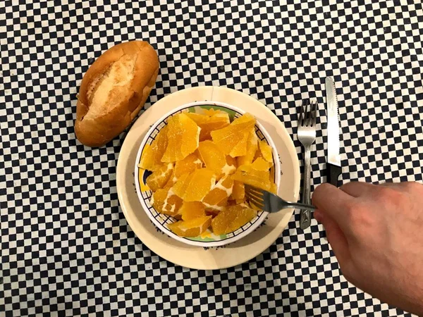 Top view of a bowl of chopped oranges with one piece of bread at the left — Stock Photo, Image