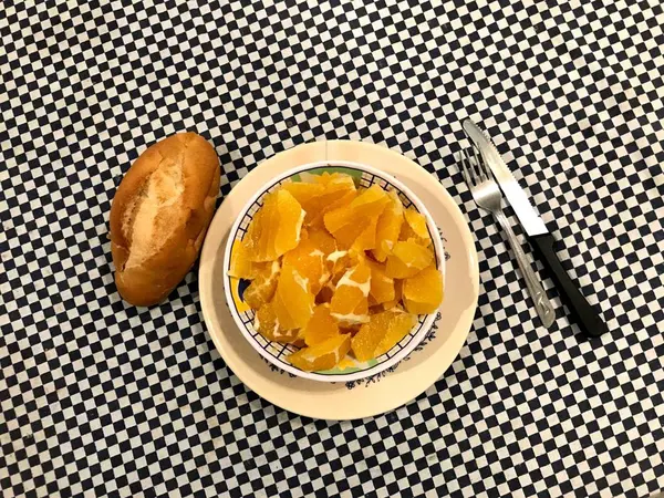 Vista superior de uma tigela de laranjas picadas com um pedaço de pão à esquerda — Fotografia de Stock