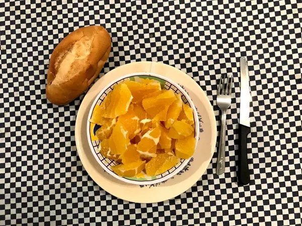 Κορυφαία θέα ενός μπολ με κομμένα πορτοκάλια με ένα κομμάτι ψωμί στα αριστερά — Φωτογραφία Αρχείου