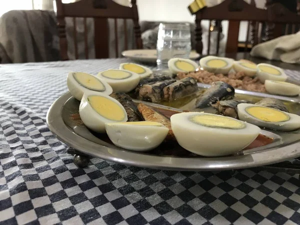 Ovo cozido cortado ao meio, sardinhas e atum em uma bandeja de aço inoxidável colocada em uma toalha de mesa quadriculada azul — Fotografia de Stock