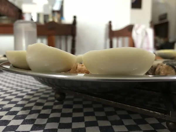 Œuf cuit coupé en deux, sardines et thon sur un plateau en acier inoxydable placé sur une nappe à carreaux bleus — Photo