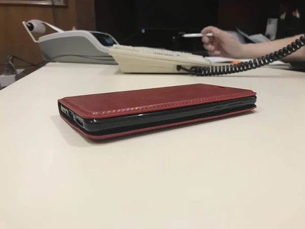 Teléfono en una caja de billetera en una mesa con teléfono de escritorio y calculadora de negocios con fondo —  Fotos de Stock