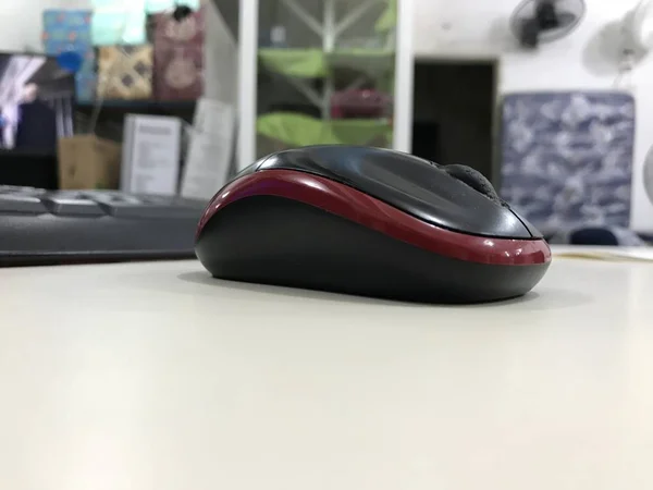 Ratón de ordenador colocado en un escritorio beige con ambiente de tienda en el fondo —  Fotos de Stock