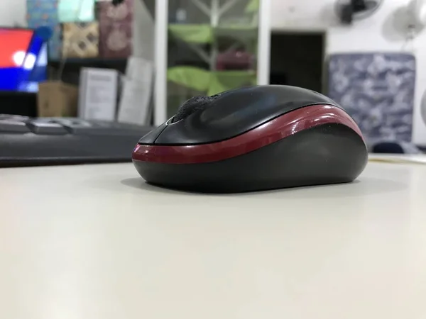 Ratón de ordenador colocado en un escritorio beige con ambiente de tienda en el fondo —  Fotos de Stock