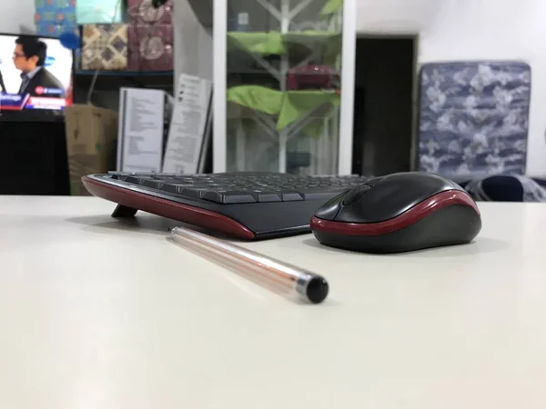 Teclado del ordenador, ratón y pluma colocados en un escritorio beige con el entorno de la tienda en el fondo —  Fotos de Stock