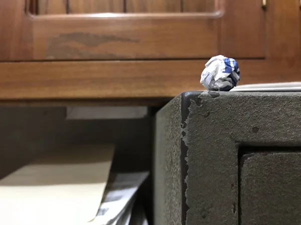 Bola de papel blanco y azul cerca del borde en la esquina de una caja fuerte de color viejo y gris —  Fotos de Stock