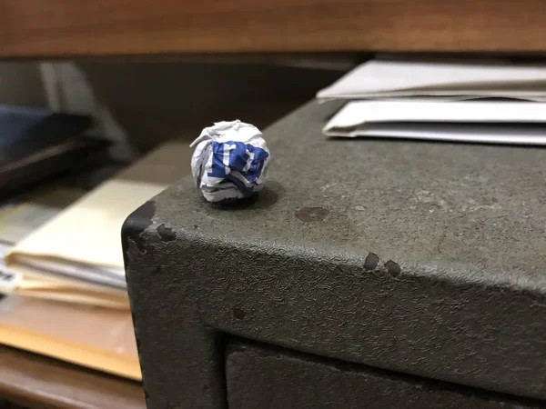 Біло-блакитний паперовий м'яч біля краю в кутку старого і сірого сейфа — стокове фото