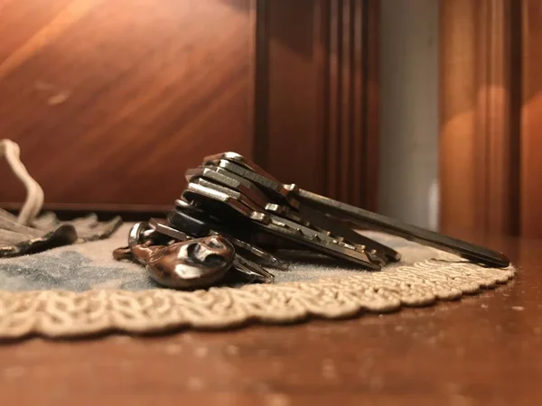 Porte-clés jambon ibérique avec clés sur un tissu en dentelle sur une table de nuit en bois — Photo