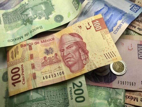 Многие смешанные мексиканские песо разбросаны по деревянному столу
