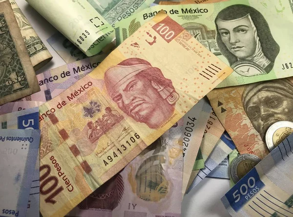 Muitas contas de peso mexicanas mistas espalhadas por uma mesa de madeira — Fotografia de Stock